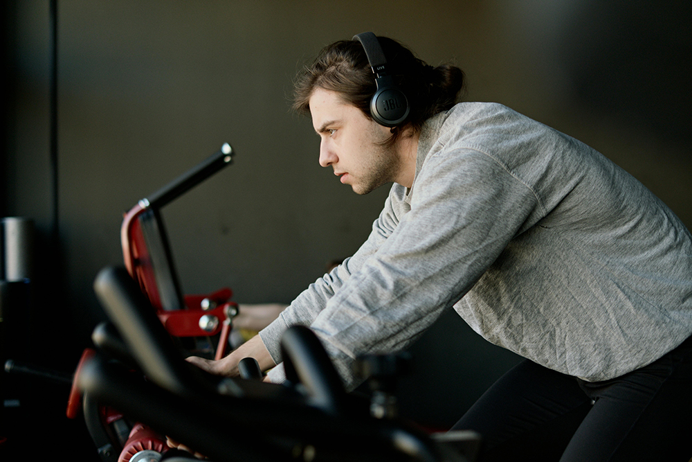 Gym guy on a bike listening to audio on headphones