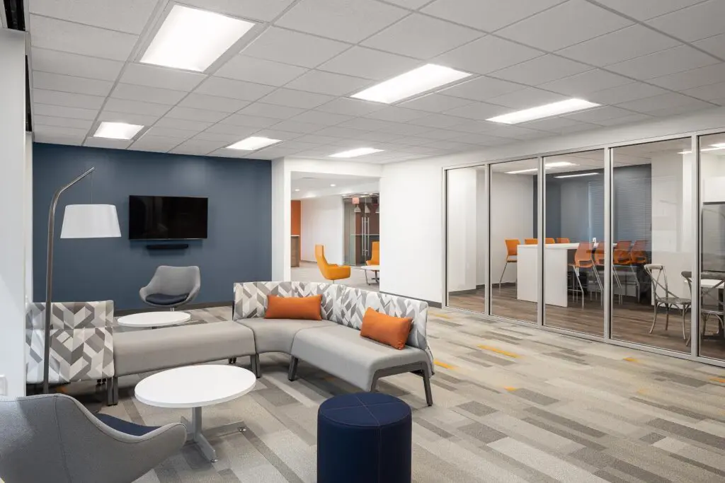 Finished commercial lounge and glass meeting rooms lit with recessed panels