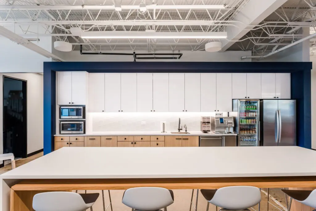 Commercial break area with an exposed ceiling, conduit runs and linear lighting