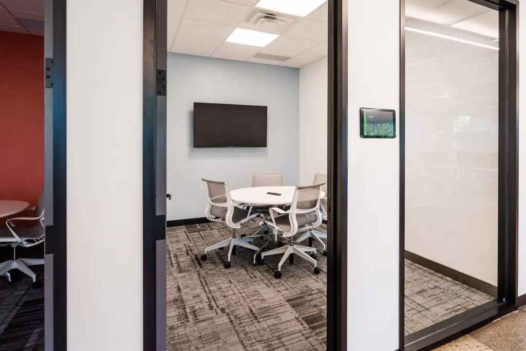 Commercial meeting room with a wall mounted control panel and recessed lighting